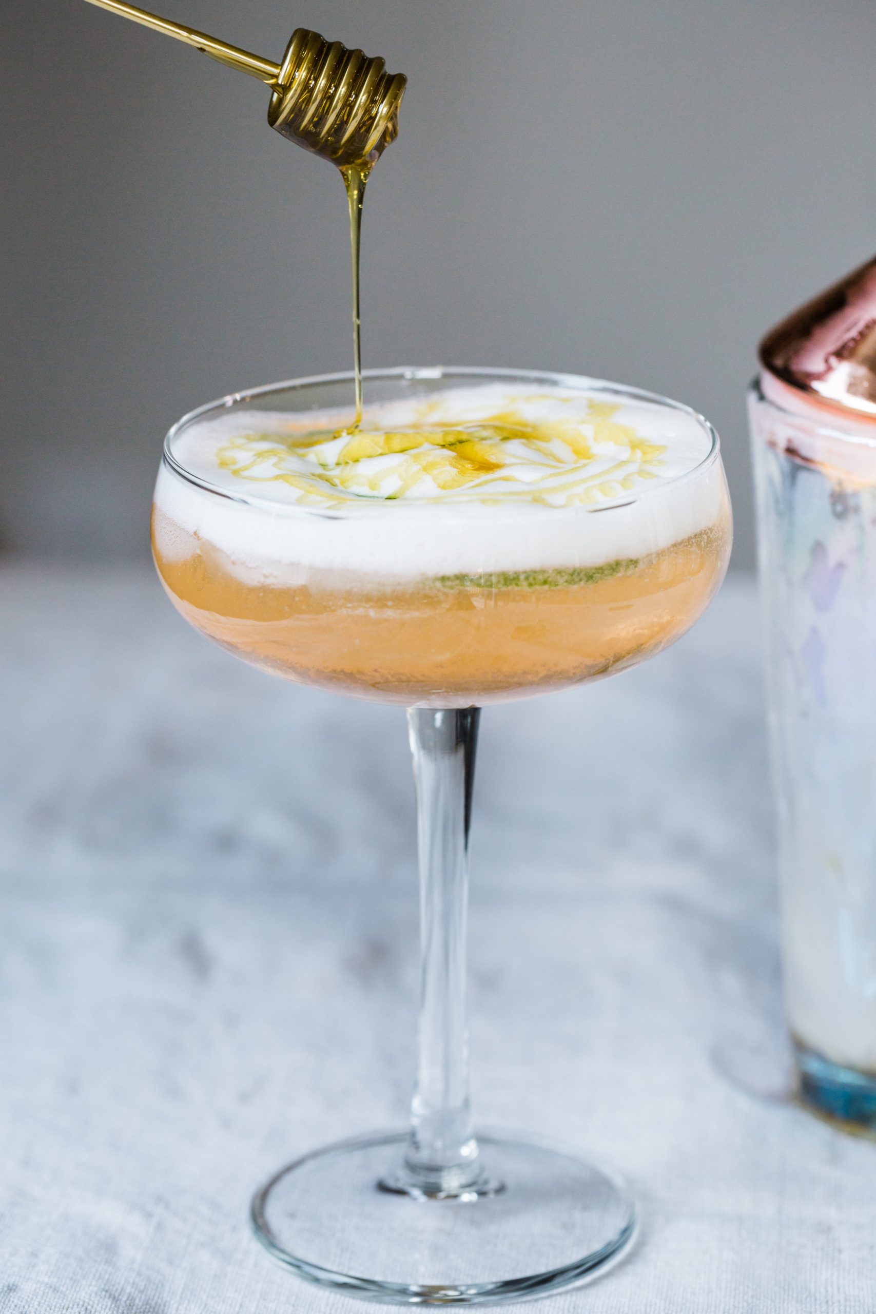 Lime and peach vodka fizz cocktail with a drizzle of honey.