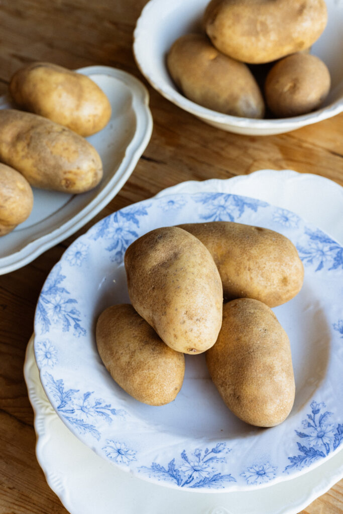 Platters of Idaho Russet potatoes sit on a wooden tabletop.