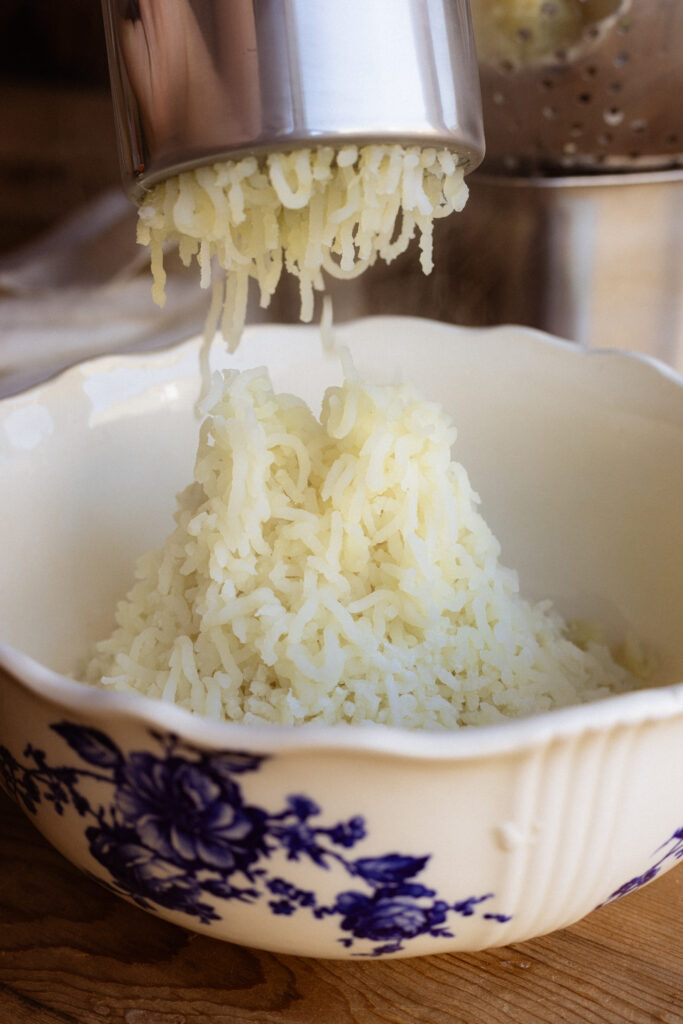 A pile of riced potatoes rest in a large serving dish.