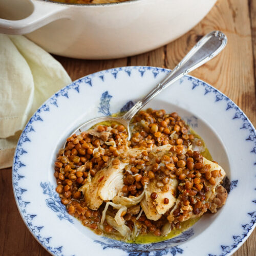 French-Style Mustard Braised Chicken & Lentils served in an antique bowl with a silver spoon.