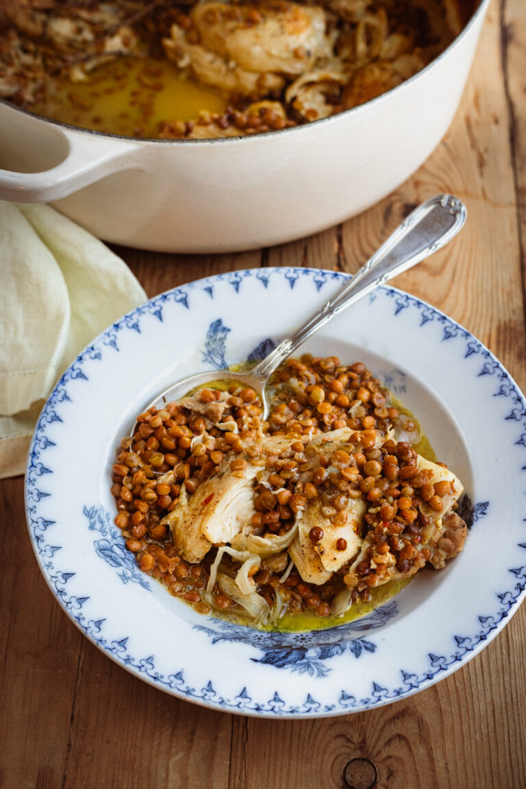 French-Style Mustard Braised Chicken & Lentils served in an antique bowl with a silver spoon.