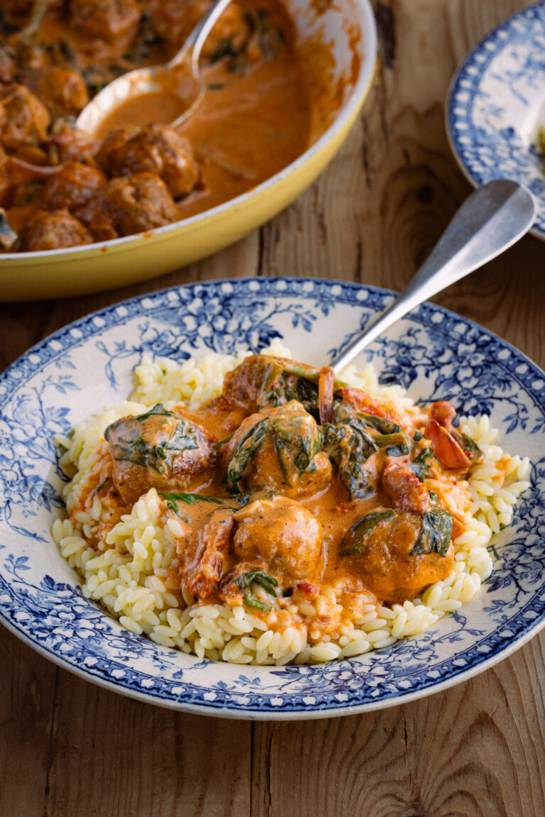 Marry Me Chicken Meatballs in sauce with orzo in an antique bowl on a tabletop.